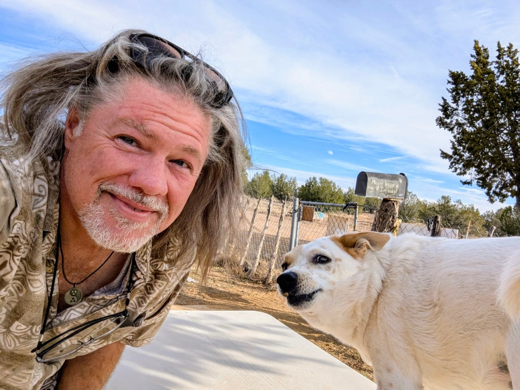 Clifford and his dog Sandy outside under a bright desert sky at A Spark in the Dark Campground.